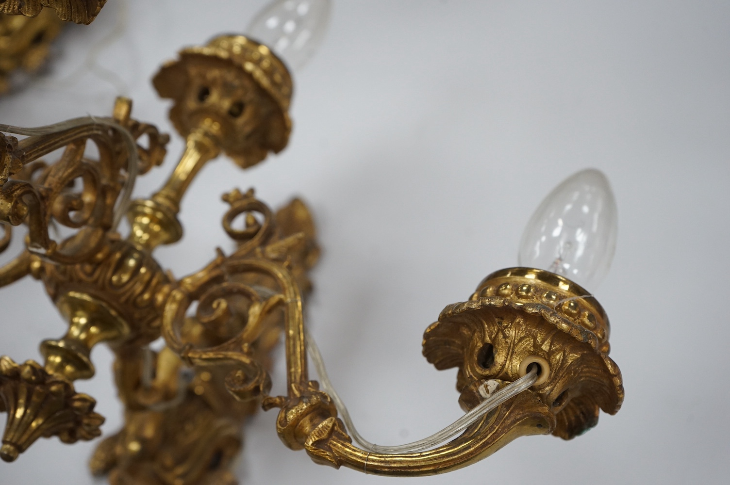 A set of four Baroque style, three branch brass wall lights. 44cm wide x 28cm high. Condition - good